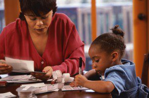 Daughter helping her mother prepare bills (Photo: Photodisc/Keith Brofsky)