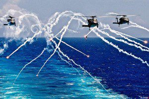 FLARE FIRE - MH-60S Seahawk helicopters fire flares as they approach the aircraft carrier USS Abraham Lincoln under way in the Atlantic Ocean, Aug. 2, 2012. U.S. Navy photo by Seaman Zachary A. Anderson