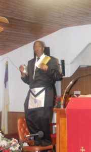 Pastor Frank Giddens speaks the word with a bible in his hand and a Masonic Apron around his waist. Credit. Karsceal Turner-WONO