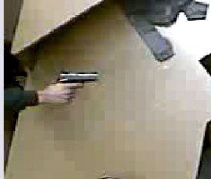 Video still of armed robber pointing gun 