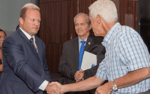 Former Gov. Charlie Crist (r) greets Attorney Dan Newlin (l) at at fundraiser, while Tim German, father of Windermere Police Officer Robert German, looks on at the Law Offices of Dan Newlin, Orlando, Florida, October 16, 2014. (Photo credit: Roberto Marquez)